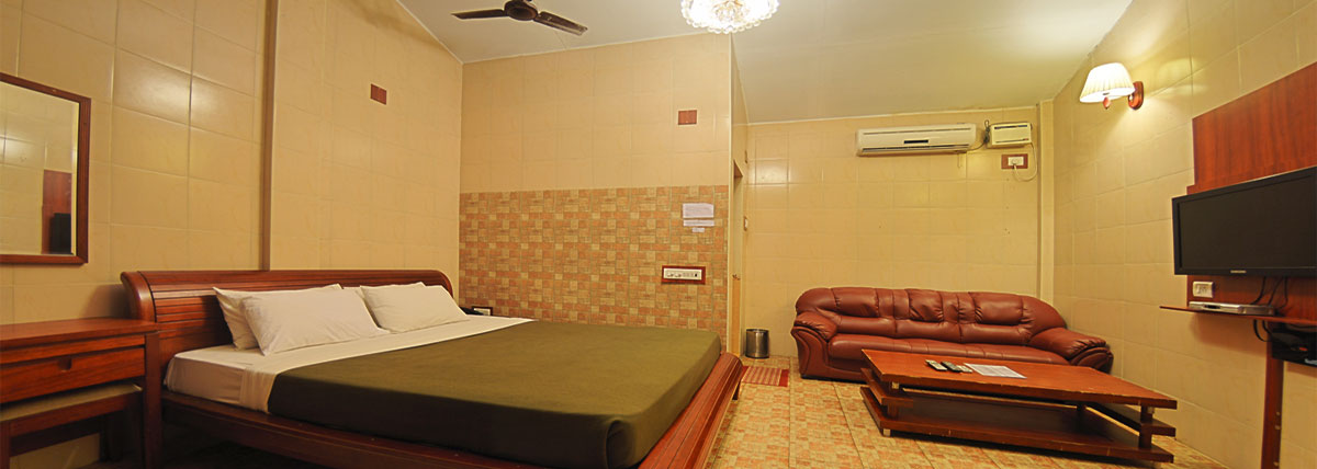 Spacious oceanside cottage room with a kingsize bed, television with set top box, Sofa and table, dressing table with mirror, fan and airconditioner in Bluebay beach resort, ECR, Chennai